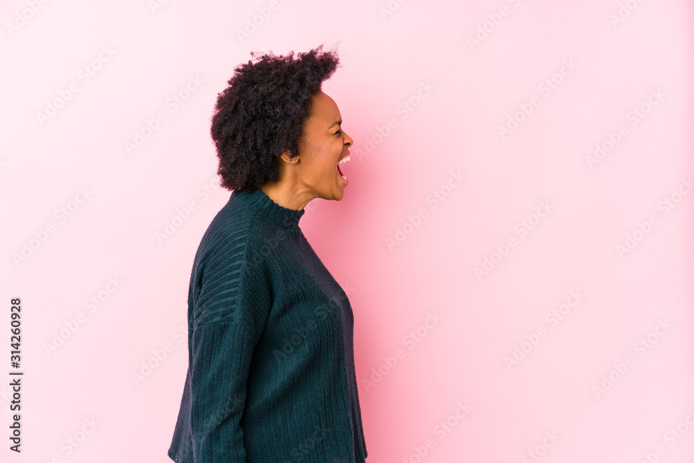 Middle aged african american woman against a pink background isolated shouting towards a copy space Middle aged african american woman against a pink background isolated shouting towards a copy space