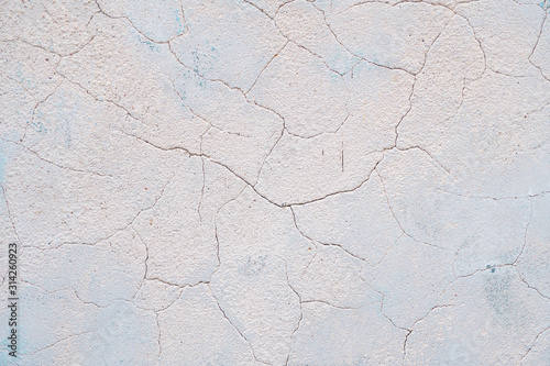 old light brown plaster in cracks. Light brown wall with blue spots. texture with cracks