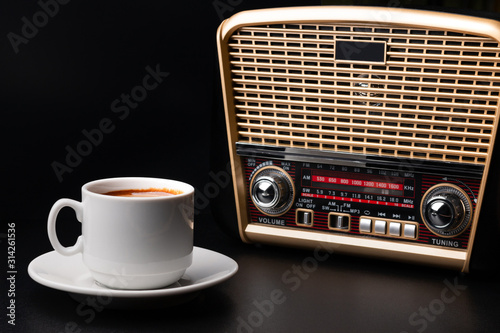 Cup of coffee and radio receiver on black background