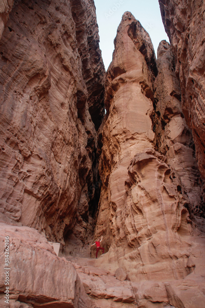 Obraz premium Caucasian male traveler in a red T-shirt posing on a background of sandy rock Solomon Pillars in Timna National Park, Israe