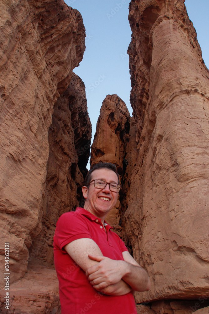 Caucasian male traveler in a red T-shirt posing on a background of sandy rock Solomon Pillars in Timna National Park