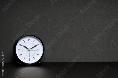 Close up of black clock on black background with copy space for text