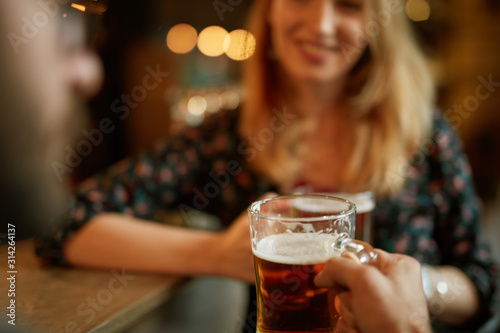 Close up of couple toasting with beer while standing at pub.