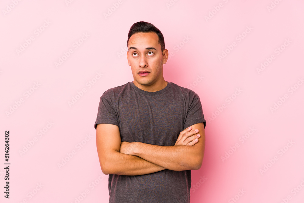 Yooung latin man posing in a pink backgroundtired of a repetitive task. Yooung latin man posing in a pink backgroundtired of a repetitive task.
