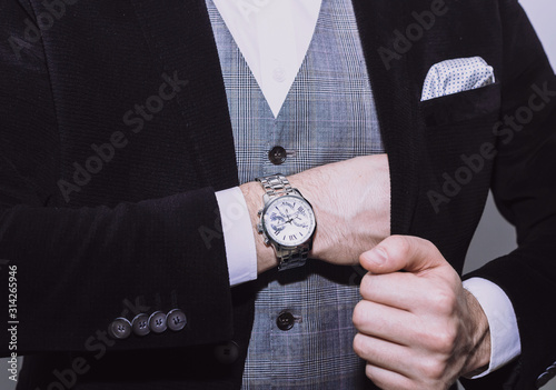 closeup fashion image of luxury watch on wrist of man.body detail of a business man.Man's hand in a grey checkered suit closeup at white background.Not isolated