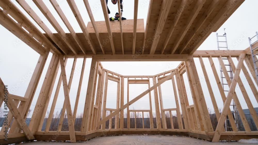 Timelapse view of interior of frame house under construction. Builders are covering the second floor with plywoods