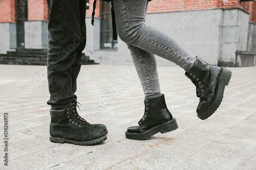 Legs of a guy and a girl standing on a wet asphalt road