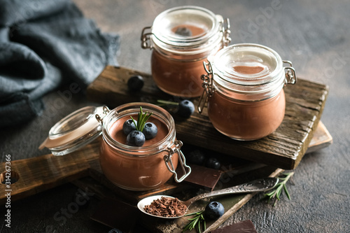 Chocolate mousse in glass jar with berries on a dark background copy space. Homemade dessert.