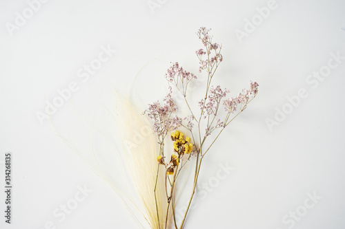 Fototapeta Naklejka Na Ścianę i Meble -  Bouquet of dried wild flowers on white table background top view.