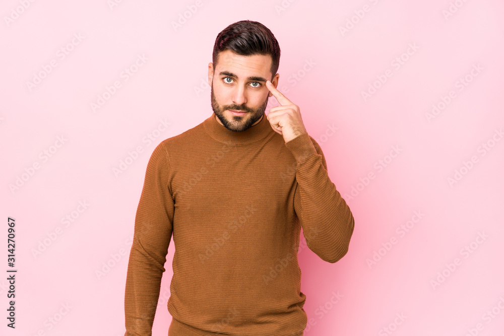Young caucasian man against a pink background isolated pointing temple with finger, thinking, focused on a task.