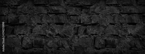 Black grunge background. Old dark gray brick wall. Close-up. Black stone background. Sloppy uneven brickwork. Distressed masonry. Black abstract grunge banner.