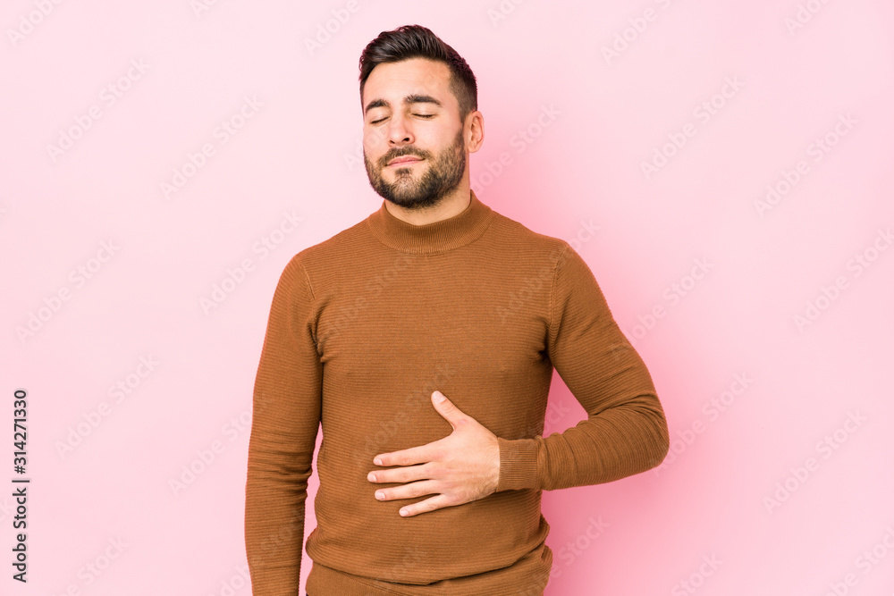 Young caucasian man against a pink background isolated touches tummy, smiles gently, eating and satisfaction concept. Young caucasian man against a pink background isolated touches tummy, smiles gently, eating and satisfaction concept.