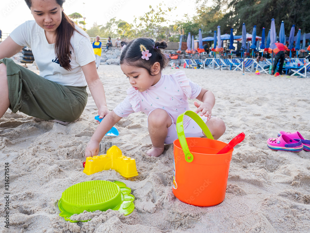Little Girl and Mother Playing Sand at The Beach