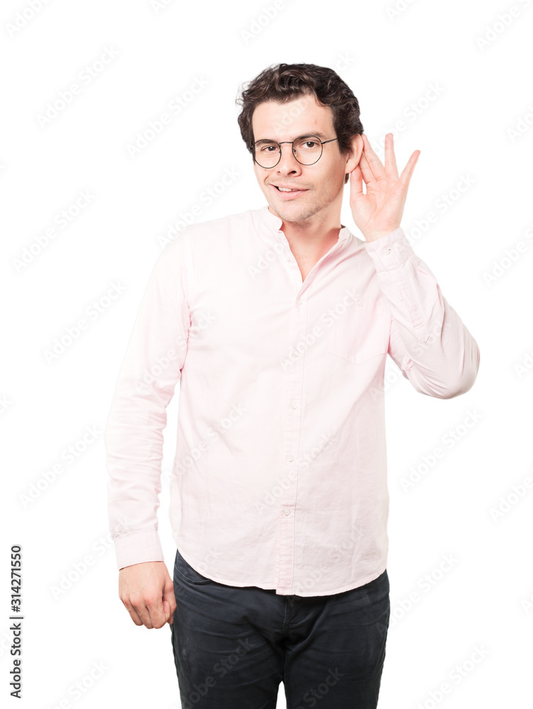 Happy young man smiling and making a gesture of trying to hear something Happy young man smiling and making a gesture of trying to hear something