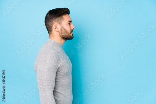 Young caucasian man against a blue background isolated gazing left, sideways pose. photo