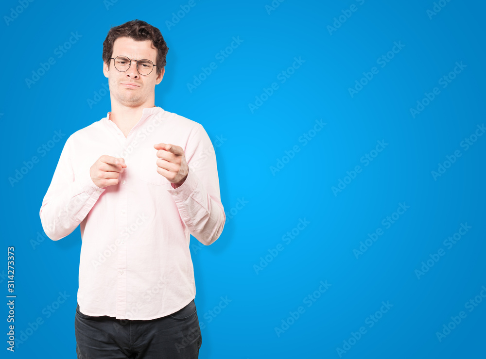 Hesitant young man pointing at you with his finger Hesitant young man pointing at you with his finger
