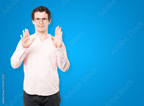 Happy young man making a gesture of stop with his palm