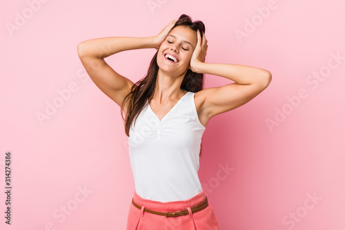Young cute woman laughs joyfully keeping hands on head. Happiness concept.