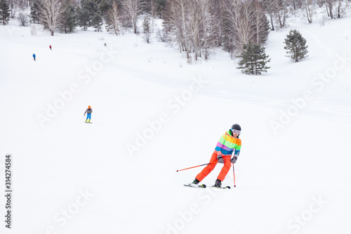 A woman skier slides down the mountain over white snow in a sports tourist base Turquoise Katun. Seasonal sports.