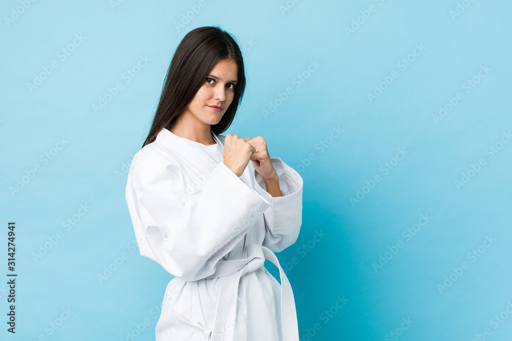 Young caucasian woman practicing karate isolated on a blue background Young caucasian woman practicing karate isolated on a blue background
