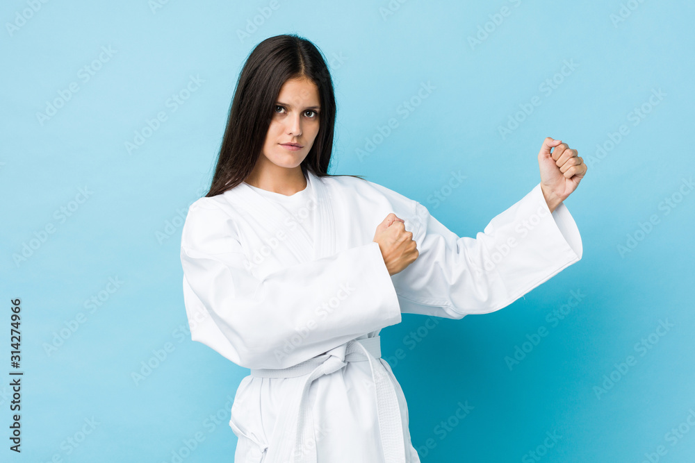 Young caucasian woman practicing karate isolated on a blue background Young caucasian woman practicing karate isolated on a blue background