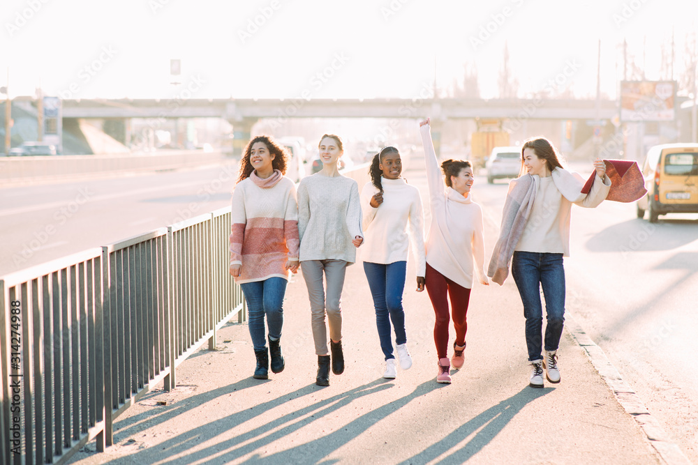 Multiracial group of friends walks and has a fun on city street. Multiracial group of friends walks and has a fun on city street.