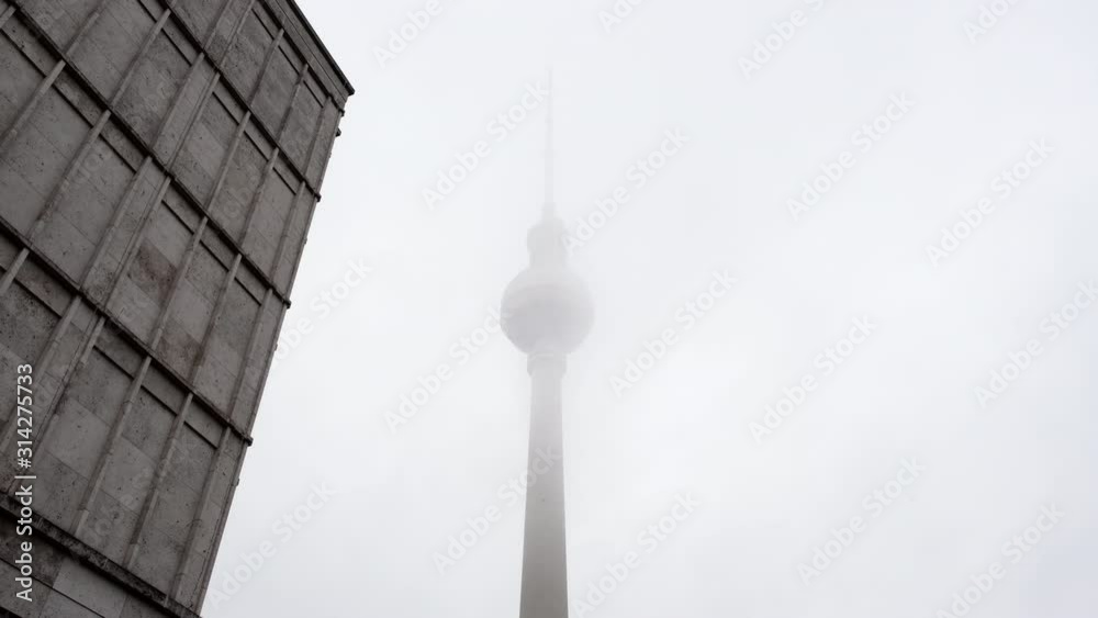 Berlin TV tower in foggy weather with clouds quickly floating through it Berlin TV tower in foggy weather with clouds quickly floating through it