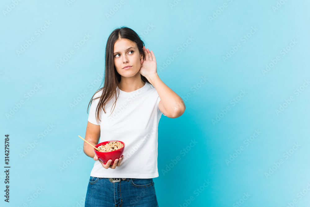 Young caucasian woman holding a cereals bowl trying to listening a gossip. Young caucasian woman holding a cereals bowl trying to listening a gossip.