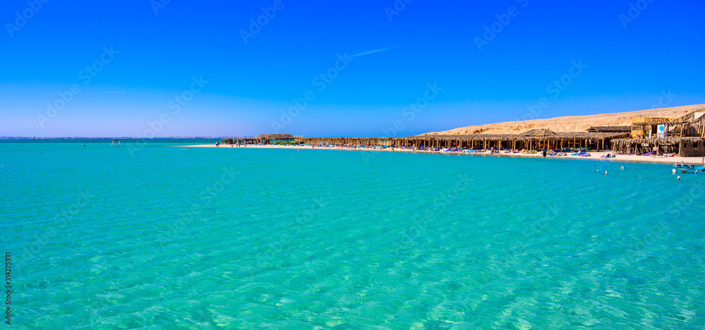 Orange Bay Beach with crystal clear azure water and white beach - paradise coastline of Giftun island, Mahmya, Hurghada, Red Sea, Egypt.