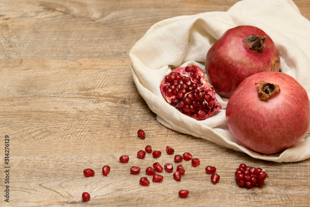 Pomegranates and seeds in the bag. Rustic wooden background. Pomegranates and seeds in the bag. Rustic wooden background.
