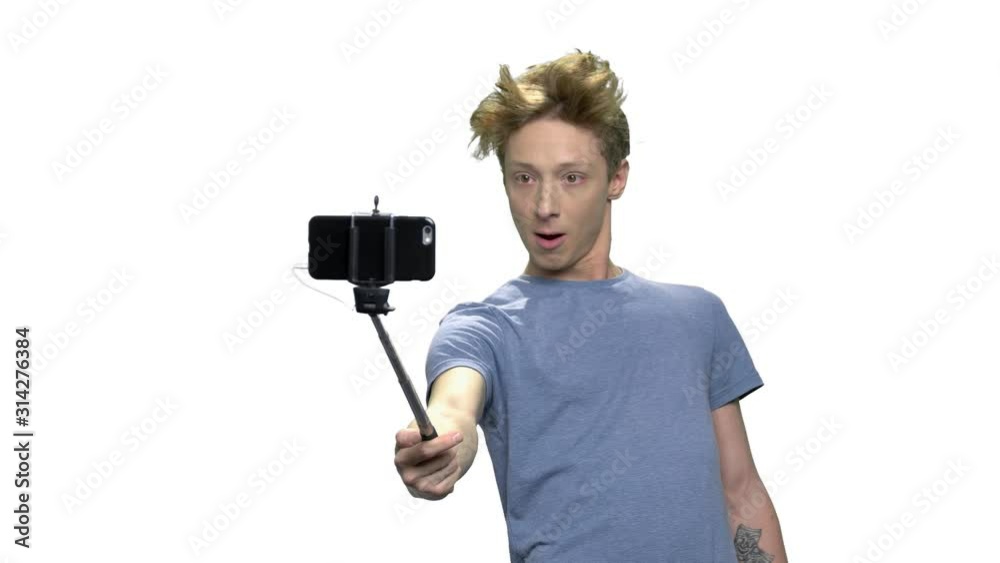 Young teenage boy making selfie. Funny teen guy making grimace while posing for camera over white background. Youth, technology and fun. Young teenage boy making selfie. Funny teen guy making grimace while posing for camera over white background. Youth, technology and fun.
