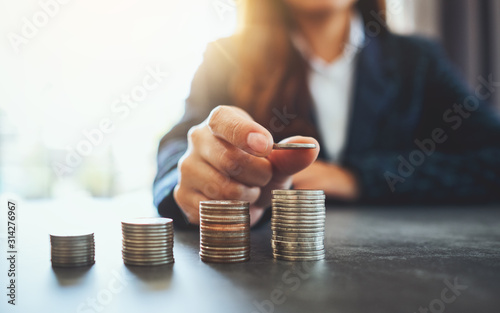 Businesswoman holding and stacking coins on the table