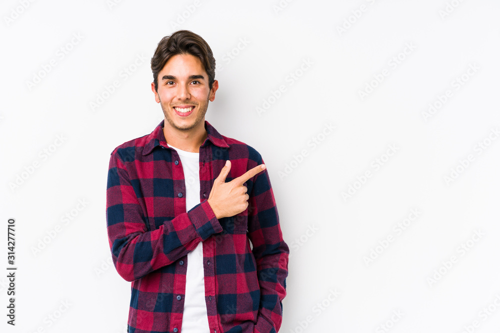 Young caucasian man posing in a white background isolated smiling and pointing aside, showing something at blank space. Young caucasian man posing in a white background isolated smiling and pointing aside, showing something at blank space.
