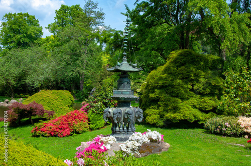 An asian-styled fountain statue surrounded by flowers in a park