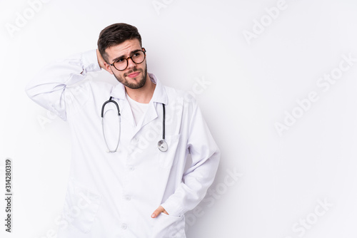 Young caucasian doctor man isolated touching back of head, thinking and making a choice.