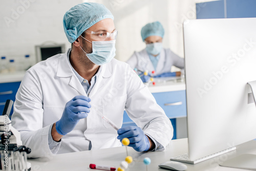 selective focus of genetic consultant doing dna test and looking at computer in lab