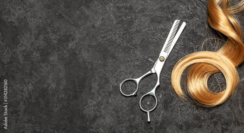 The hairdresser. Scissors and curl of hair on a black background
