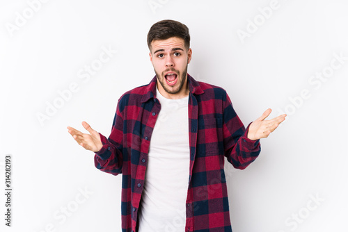 Young caucasian man posing in a white background isolated celebrating a victory or success, he is surprised and shocked.