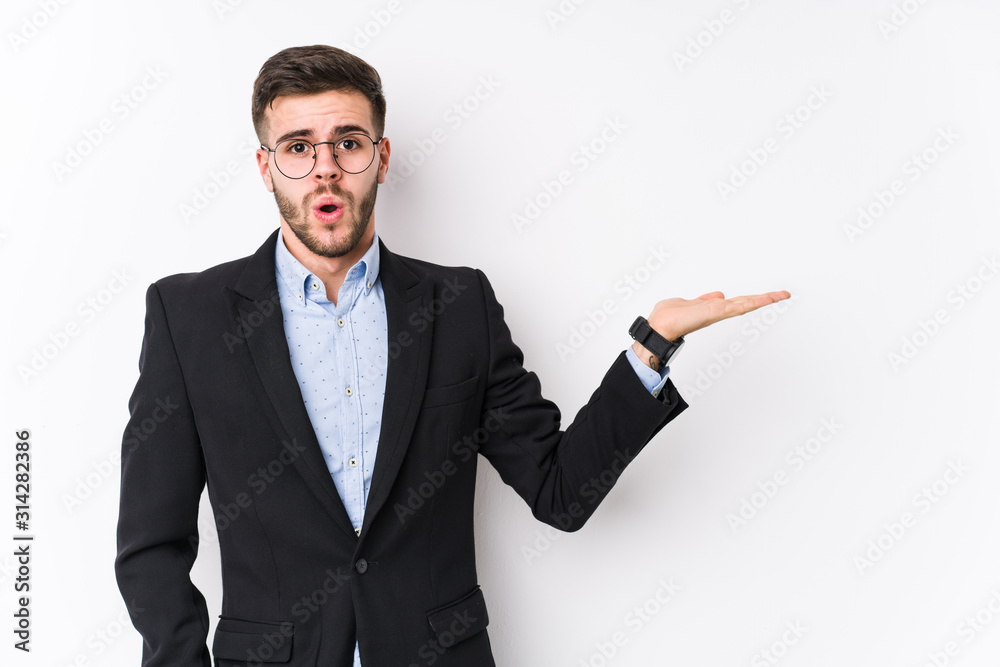 Young caucasian business man posing in a white background isolated Young caucasian business man impressed holding copy space on palm.