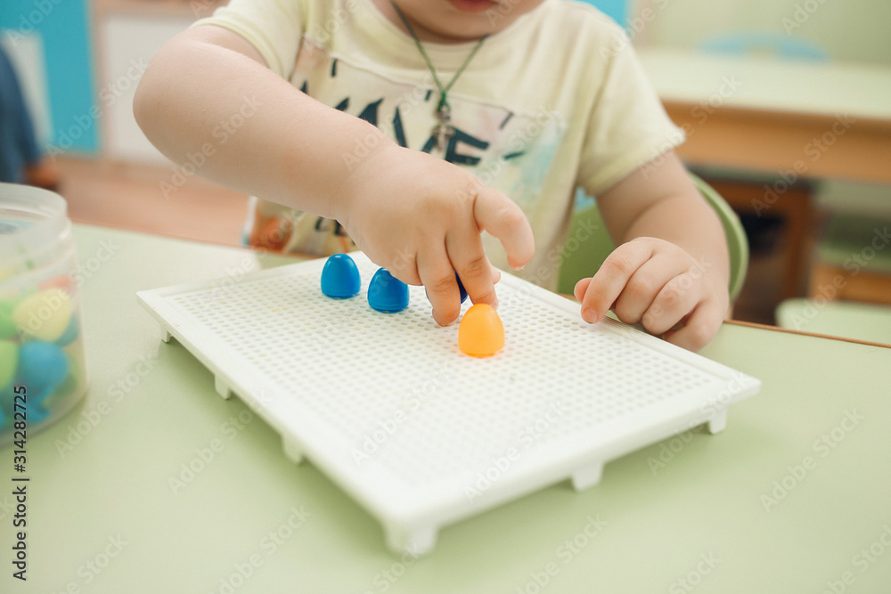 Children gathering building blocks in the kindergarten. Educational games and toys. Close up. Children gathering building blocks in the kindergarten. Educational games and toys. Close up.