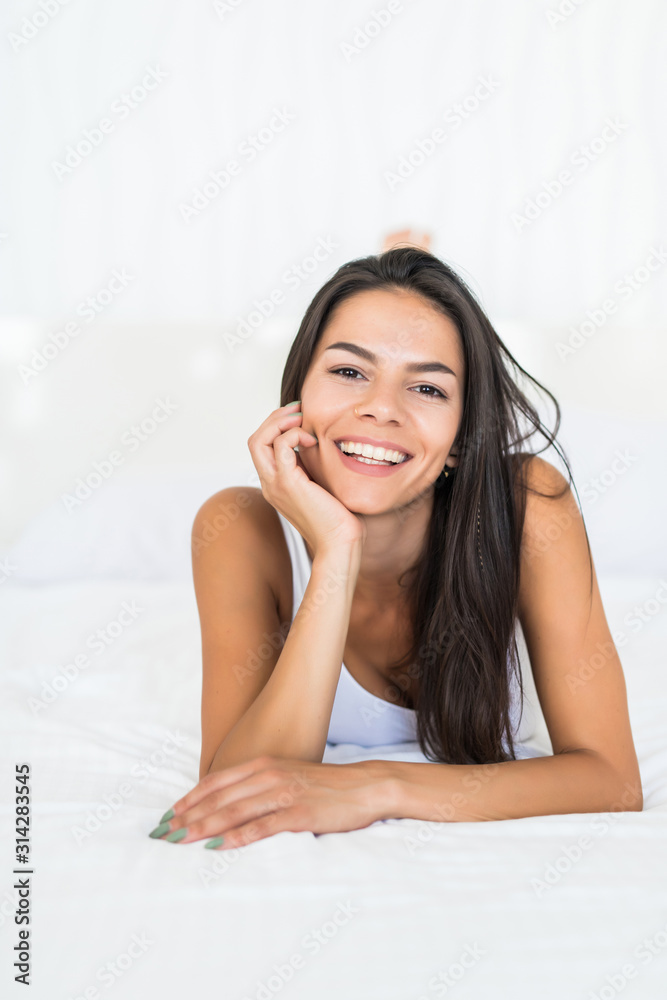 Young woman with perfect smile lying in white underwear at home in bed Young woman with perfect smile lying in white underwear at home in bed