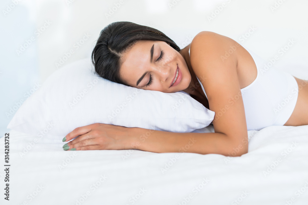 Beautiful nice woman in white lingerie lying down on the white pillow Beautiful nice woman in white lingerie lying down on the white pillow