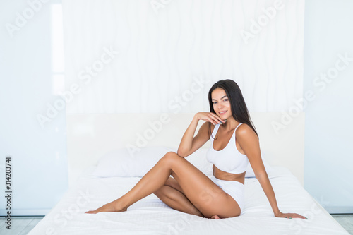 Portrait of elegant brunette woman in white underwear in bed