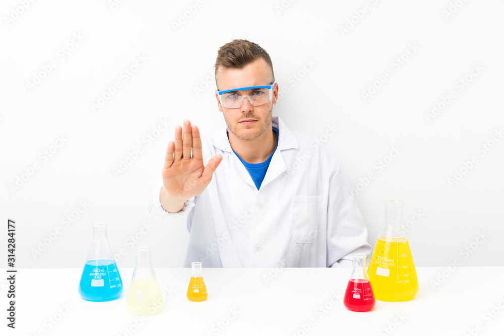 Young scientific with lots of laboratory flask making stop gesture with her hand Young scientific with lots of laboratory flask making stop gesture with her hand