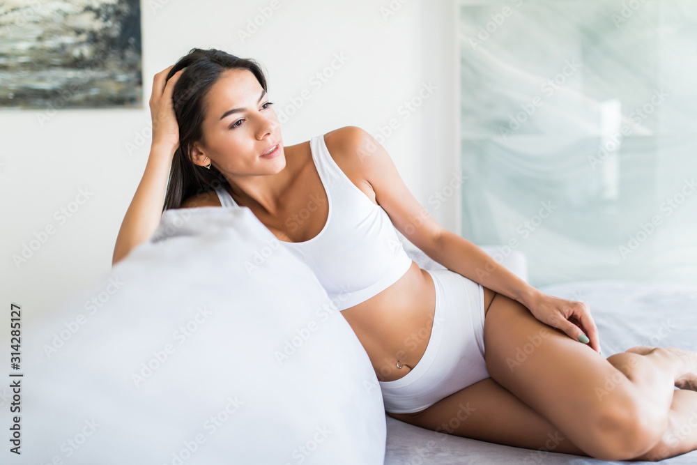 Beautiful and sexy young woman in white lingerie on the white sofa Beautiful and sexy young woman in white lingerie on the white sofa