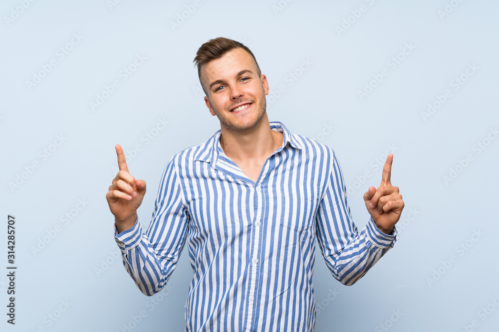 Young handsome blonde man over isolated blue background pointing up a great idea Young handsome blonde man over isolated blue background pointing up a great idea