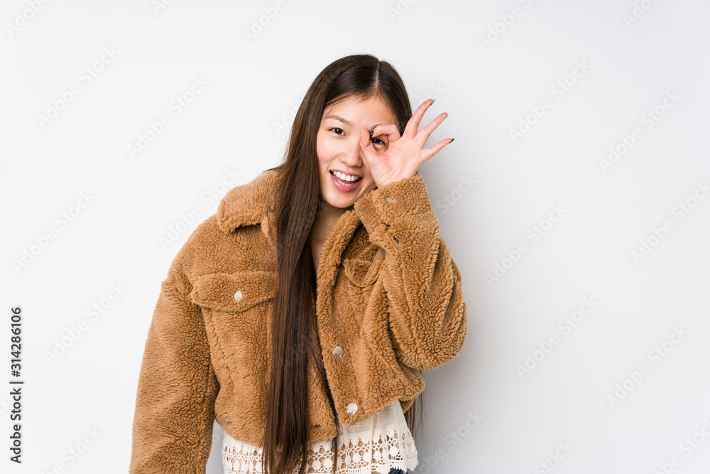 Young chinese woman posing in a white background isolated excited keeping ok gesture on eye. Young chinese woman posing in a white background isolated excited keeping ok gesture on eye.