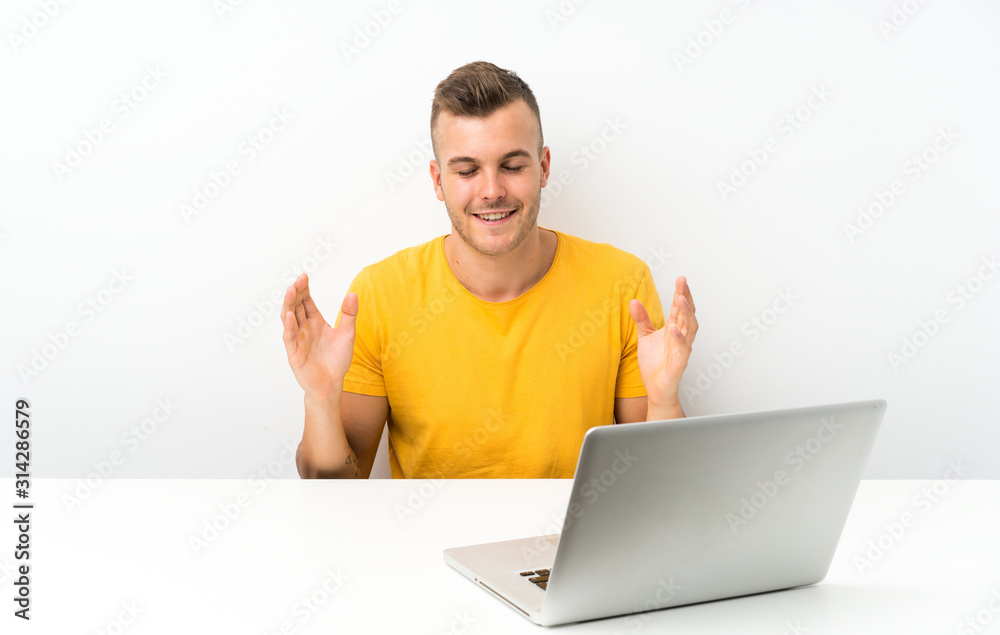 Young blonde man in a table with a laptop laughing Young blonde man in a table with a laptop laughing