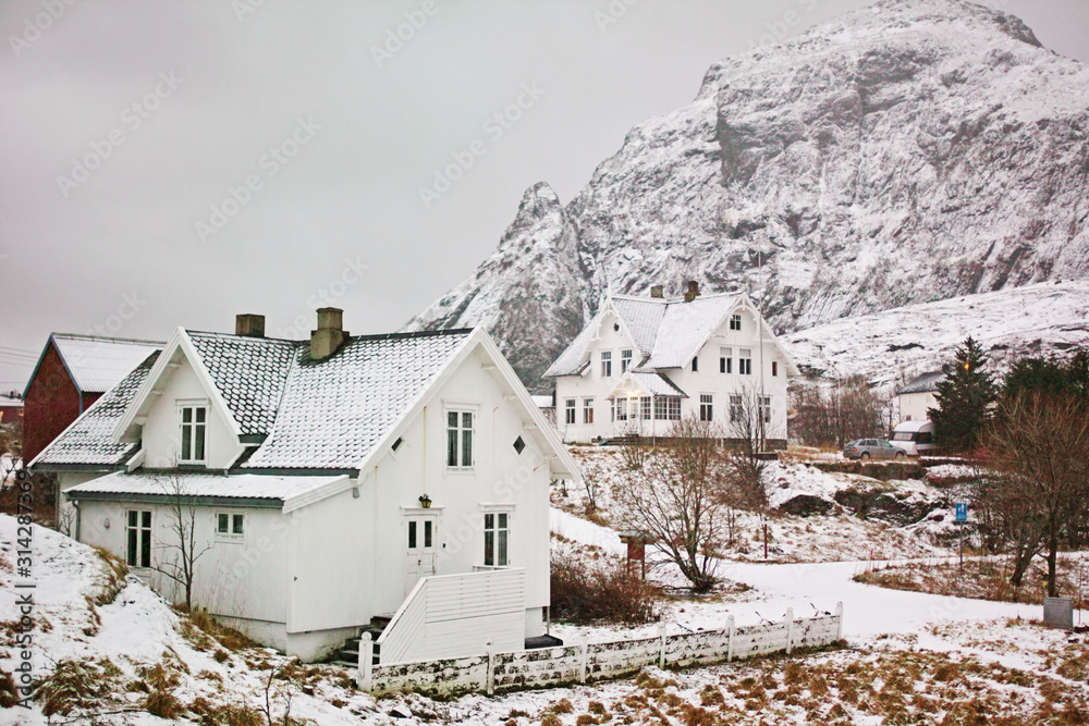 Winter village landscape with white houses and mountain covered with snow. Lofoten islands, Norway.