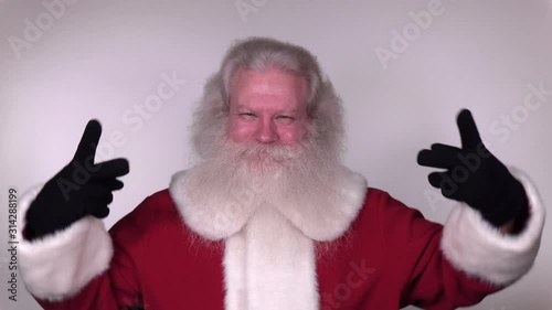 Senior Caucasian smiling man in Santa Claus suit with splendid grey hair, mustache and beard is greeting. Funny portrait of handsome European merry people on white background close up. 